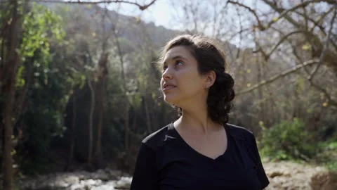 Young woman smiling while looking around surrounded by nature in forest or park Stock Footage 149435283