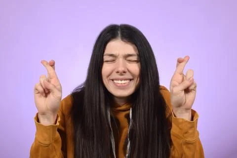 Young woman smiling while posing with fingers crossed for good luck Stock Photos