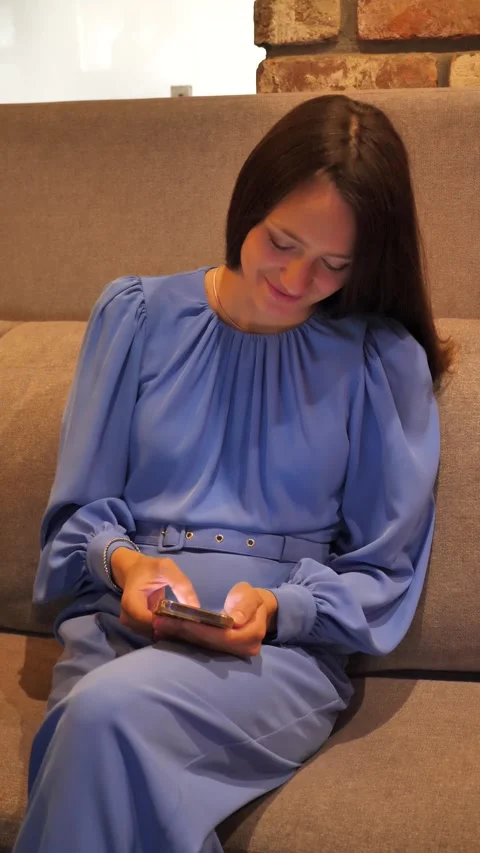 Young woman smiling while reading message using mobile phone and browsing news Stock Footage 311458494
