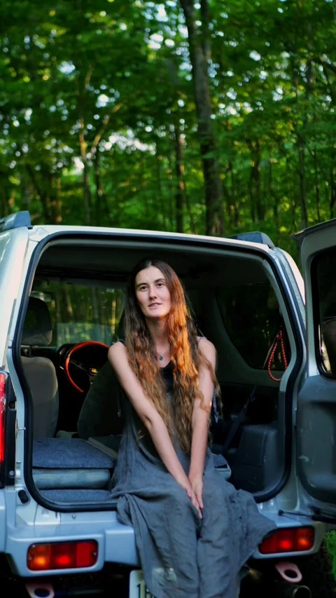 Young woman smiling while sitting in the open trunk of an SUV... Video stock 340291046