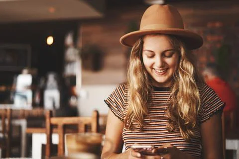 Young woman smiling while texting on mobile Stock Photos