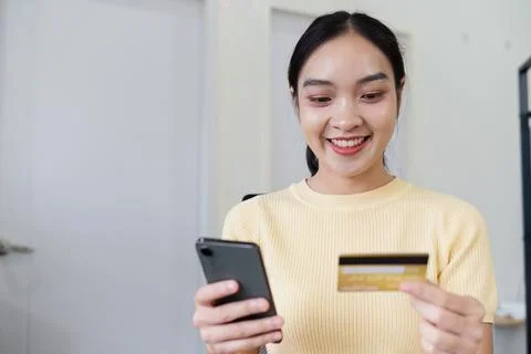 Young Woman Smiling While Using Credit Card for Online Shopping on Smartphone at Stock Photos