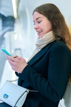 Young Woman Smiling While Using Smartphone in Modern Subway Station.Vertical Stock Photos