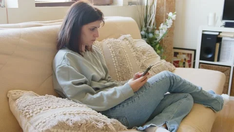 Young woman on a sofa using her smartphone Stock Footage 201087039