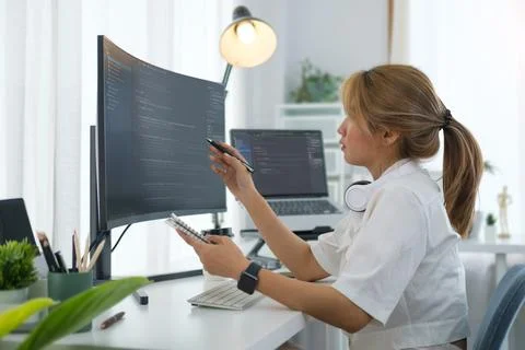Young woman software developer working with program code on wide displays a.. 库存照片