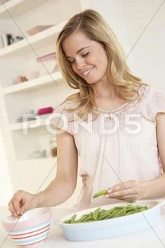 Young woman splitting pea in kitchen Stock Photos