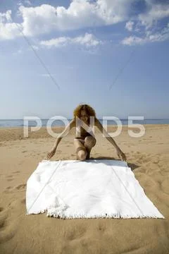 Young woman spreading bath towel Stock Photos