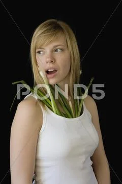 Young woman with spring onions stuffed down tank top Stock Photos