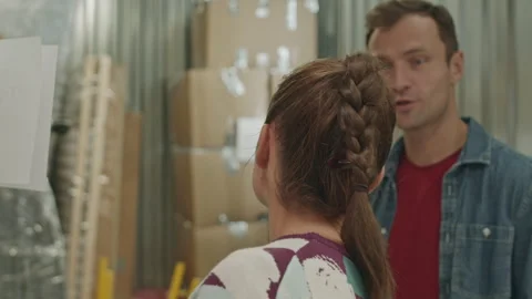 Young Woman Stacking Boxes and Talking with Husband in Self Storage Stock Footage 259828576