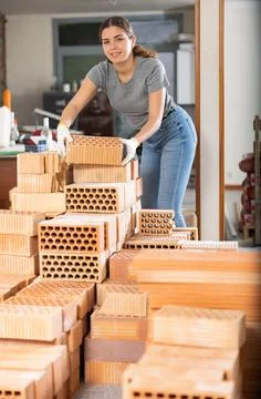 Young woman stacking bricks at construction site Stockfoto's
