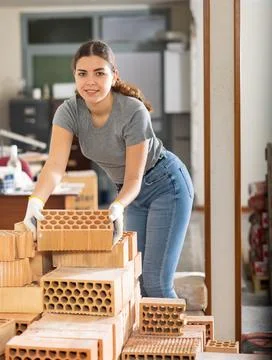 Young woman stacking bricks at construction site Stock Photos