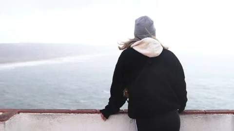 Young woman standing and looking at the sea from a viewpoint Stock Footage 230292753