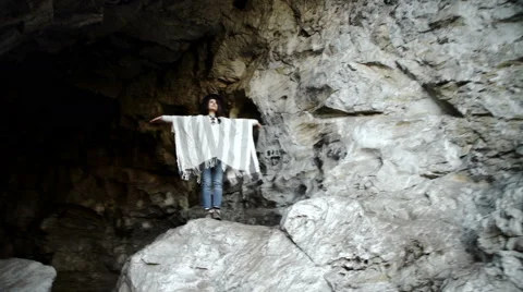 Young woman standing with backpack on cliff's edge and looking into Stock Footage 63402242
