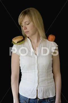 Young woman standing with a hamburger one shoulder and an apple on the other Stock Photos