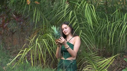 A young woman standing in the jungle holding a pineapple Stock Photos
