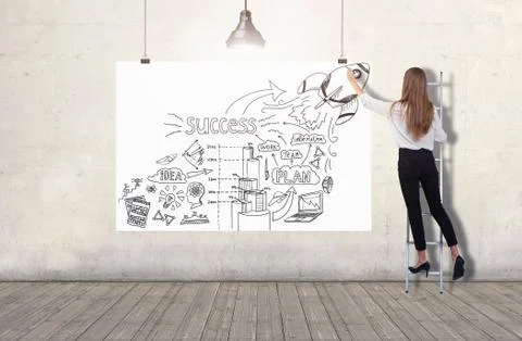 Young woman standing on a ladder and drawing a business plan sketch on a white Stock Photos