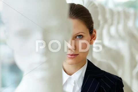 A young woman standing in line with mannequins and looking at camera Stock Photos