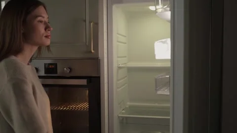 Young Woman Standing Before an Open Empty Refrigerator in a Modern Kitchen Stock-Footage 266974050