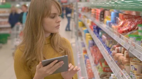 Young woman in the store checking list of products on touch pad Stock Footage 75276198