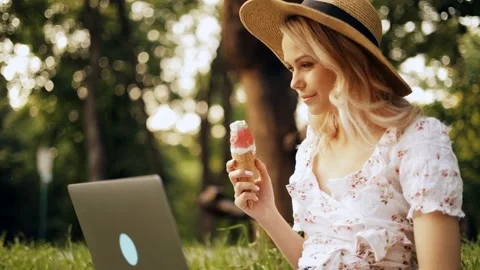 Young woman in straw hat working or studying on laptop while sitting on grass Stock Footage 242597671
