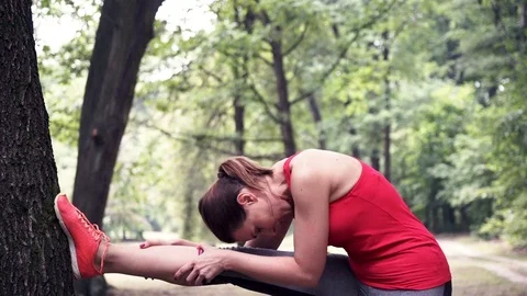 Young woman stretching legs in forest Stock Footage