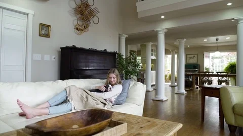 Young woman stroking a puppy while lying on a couch Video stock 83397656
