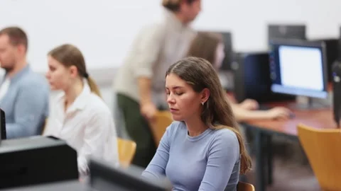 Young woman student of computer courses looks at monitor screen, types on Stock Footage 310066689