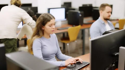 Young woman student of computer courses looks at monitor screen, types on Stock Footage 314763550