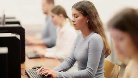 Young woman student of computer courses looks at monitor screen, types on Stock Footage 329544784