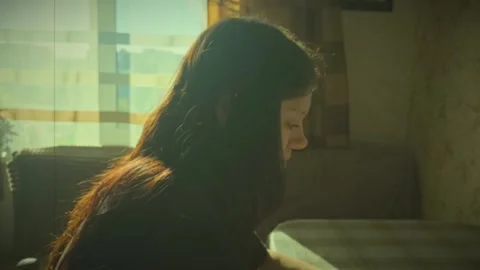Young woman studies by the window in a bright room in the afternoon Stock Footage 344331657