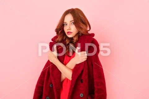 Young woman studio isolated on pink in a red dress freezed Stock Photos