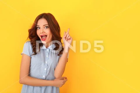 Young woman studio isolated on yellow pointing up solution Stock Photos