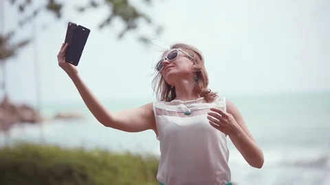 Young woman in sunglasses making selfie using smatphone while traveling by sea Stock Footage
