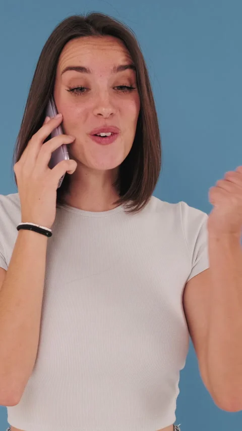 Young woman, surprised while talking on mobile phone, happy news, of Isolateed Stockbeeldmateriaal 255504941
