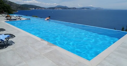 Young woman swims in infinity pool with sea view. Stock Footage