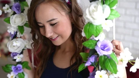 Young woman swinging on a swing decorated with flowers Stock Footage