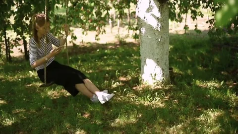 Young woman swinging on a swing while using her mobile phone Video stock 75902653