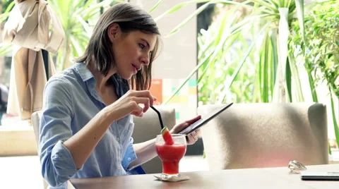 Young woman with tablet computer drinking cocktail in cafe HD Stock Footage 49416047