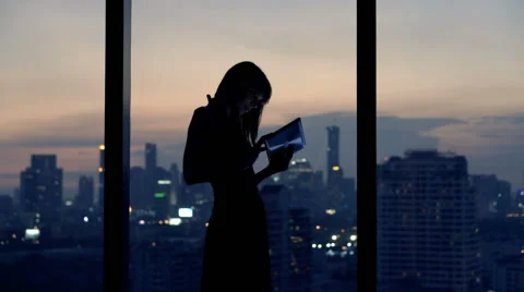 Young woman with tablet computer standing by window at night Stock Footage 62222816