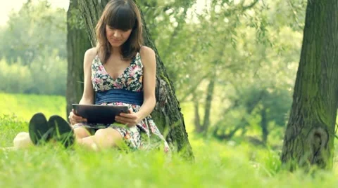 Young woman with tablet computer by the tree, dolly shot Video stock 8599096