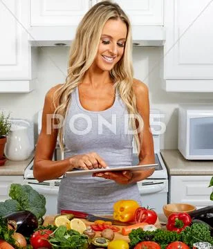 Young woman with tablet in the kitchen. Stock Photos