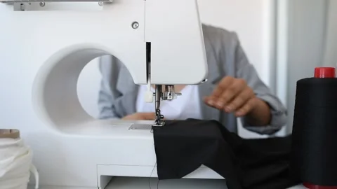 Young woman tailor is sewing on sewing machine in her mini workshop. Stock Footage