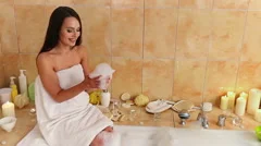 Beautiful girl in a bathtub with candles in glasses on the floor and fluffy  feathers on a white table. Stock Video Footage by ©petrunine #325087296