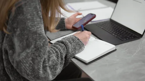 Young woman taking notes and using a smartphone Stock Footage 340925749