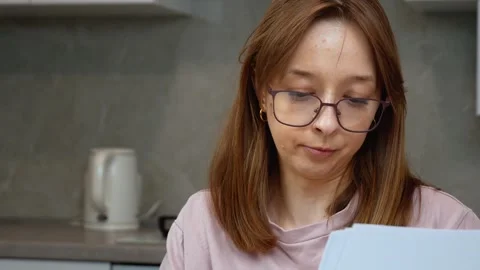 Young woman taking notes from documents at home Stock Footage 314610270