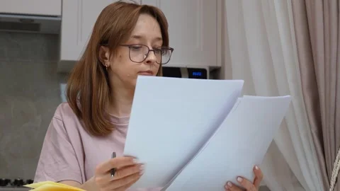 Young woman taking notes from documents at home Vídeo Stock 314610304