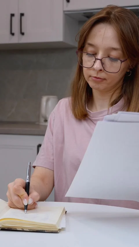 Young woman taking notes from documents at home Stock Footage 314613013