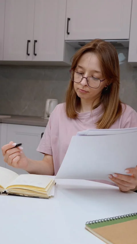 Young woman taking notes from documents at home Stock Footage 314622512