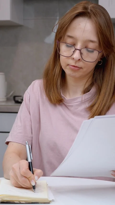 Young woman taking notes from documents at home Stock Footage 314622646