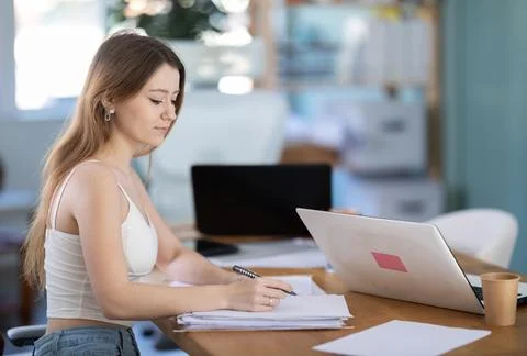 Young woman taking notes on documents in office Stock Photos